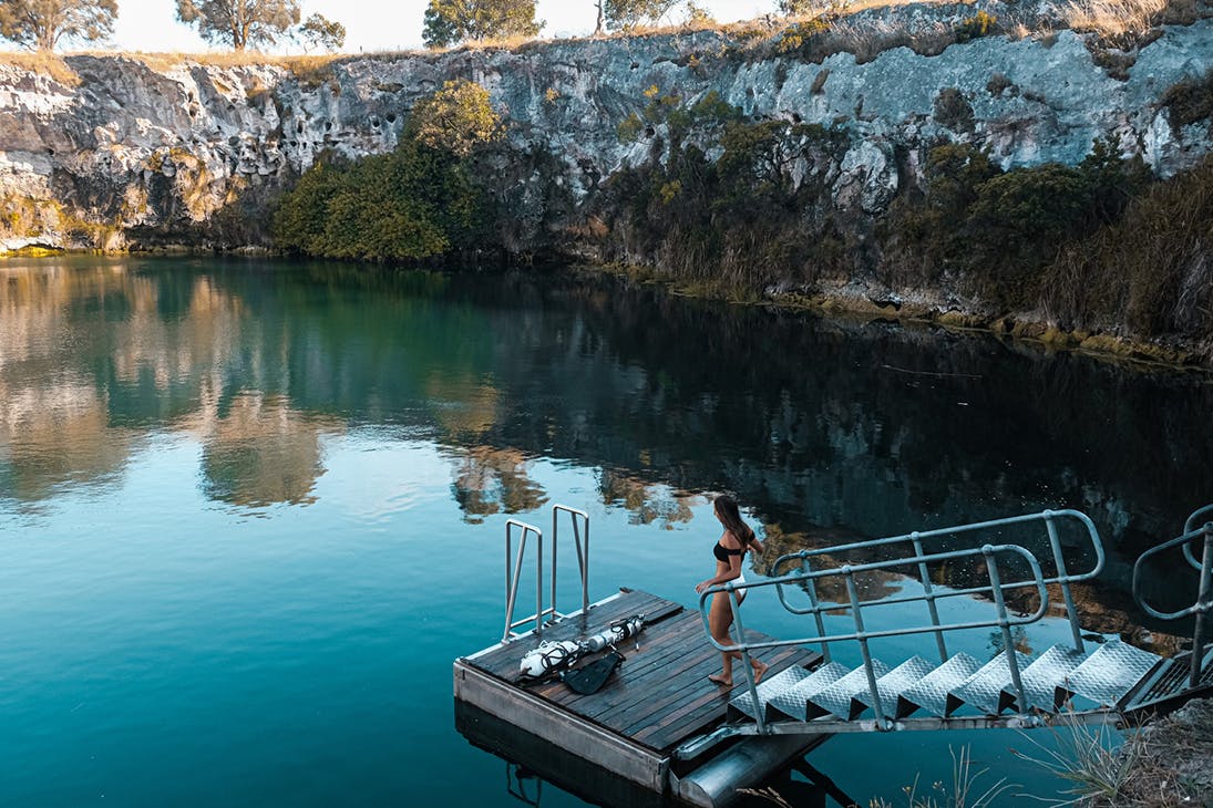 a woman walks on a pontoon at Little Blue Lake